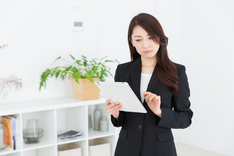 タブレットを見つめるスーツの女性